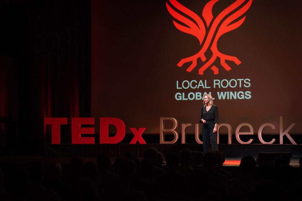 Valeria Told auf der Bühne vor dem LOCAL ROOTS GLOBAL WINGS-Motiv