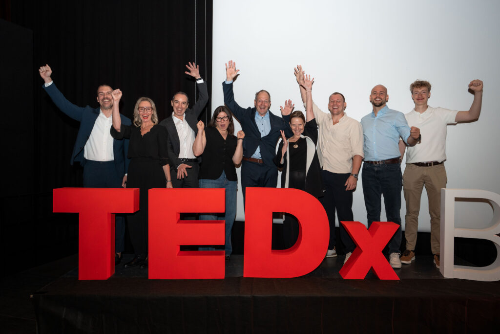 Das TEDxBruneck-Team auf der Bühne hinter dem TEDx-Schriftzug